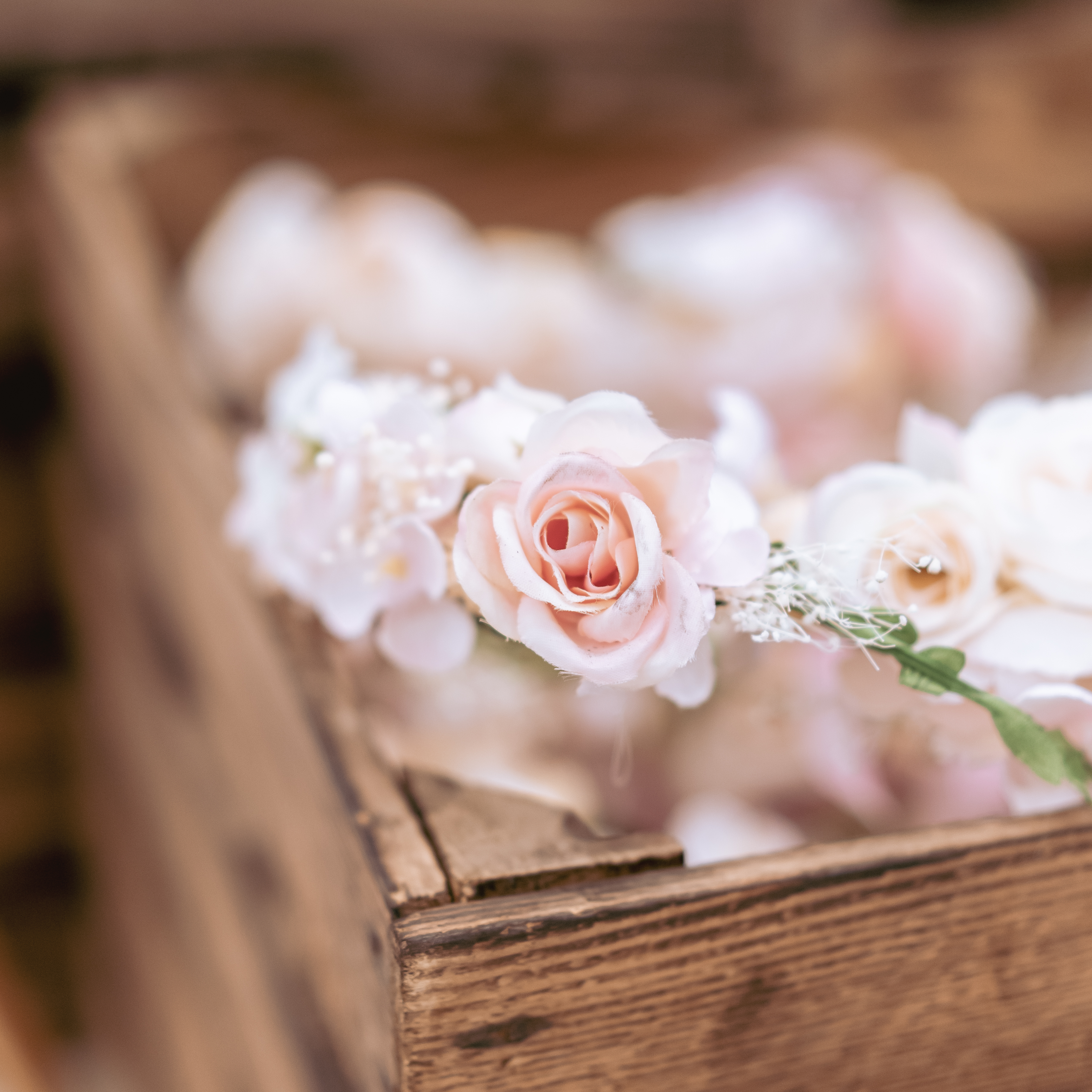 hellfarbiger Blumenkranz dekoriert in einer Holzkiste